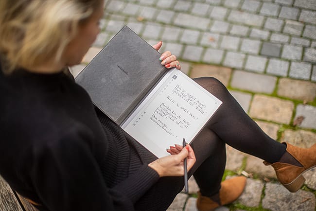 Autentisk øyeblikk av en kvinne som reflekterer og skriver i en journal, omgitt av et naturlig og harmonisk miljø