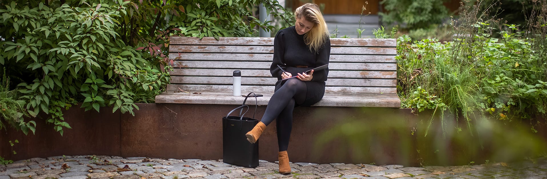 Personlig merkevarebilde av en solopreneur og bedriftseier som sitter i en urban park, reflekterer og skriver kreativt, med et naturlig og autentisk uttrykk