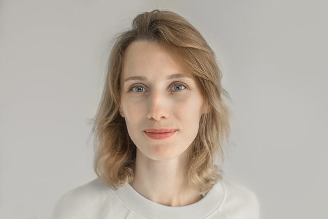 Profilbilde av en profesjonell norsk kvinnelig fotograf, fanget i en naturlig og autentisk positur, med et vennlig og imøtekommende smil, perfekt som profesjonelt profilbilde for bedrift